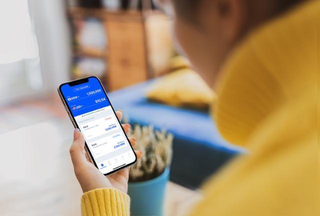 A user checks account balances and manages international money transfers through a mobile finance app while living abroad.